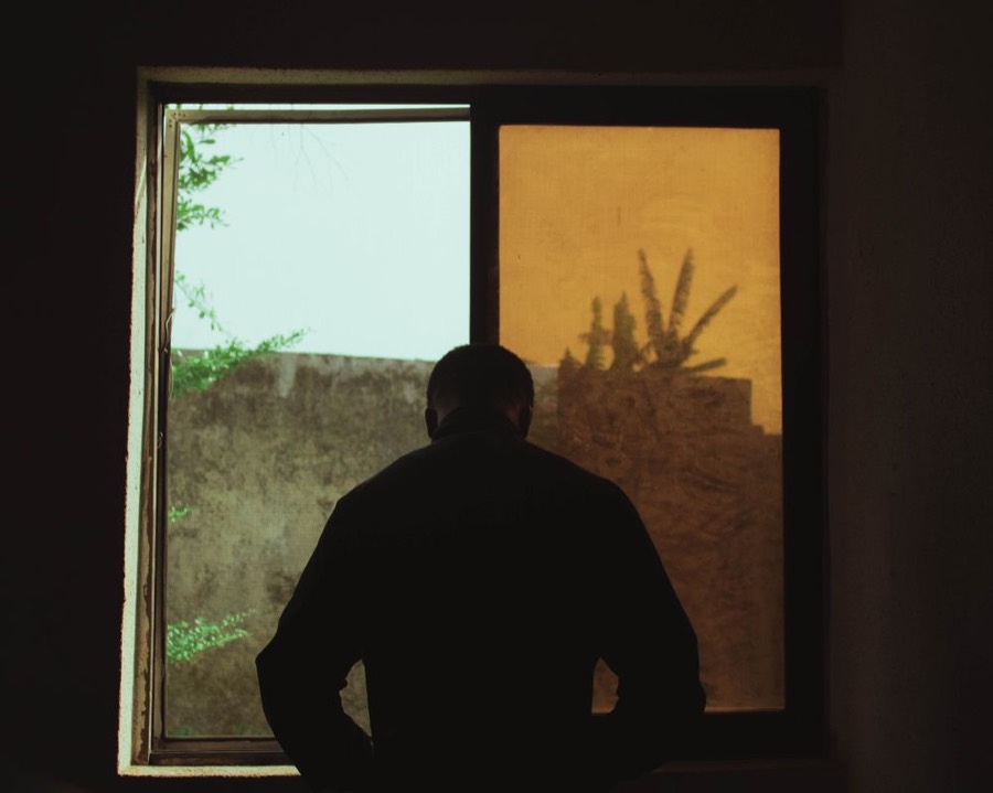 A man's silhouette at a window, deep in thought